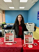 Woman smiling standing in front of event table.